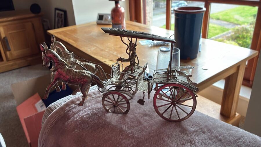 An ornate brass model of a horse-drawn carriage